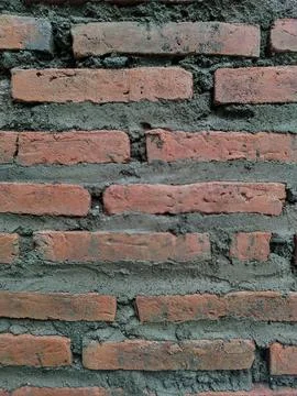 Close-up view of a rustic red brick wall with rough grey mortar Stock Photos