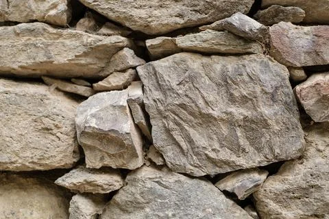 Close-up view of a rustic stone wall featuring various sizes and shapes of Stock Photos