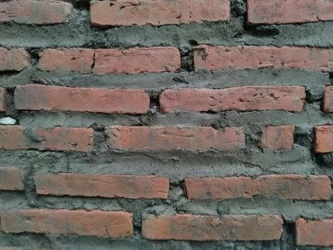 Close-up view of a rustic, weathered brick wall with rough mortar Stock Photos