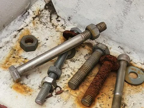 Close view of rusty and stainless bolts on industrial surface Stock Photos