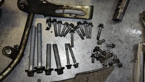 Close-Up View of Rusty Bolts and Studs Laid Out on Auto Workshop Floor Stock Footage 346411298