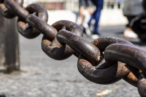 Close up view of rusty metal chain links on a blurred square at background Stock Photos