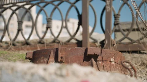 Close View of Rusty Metal Object with Ornate Fence and Urban Background Stock Footage 279676772