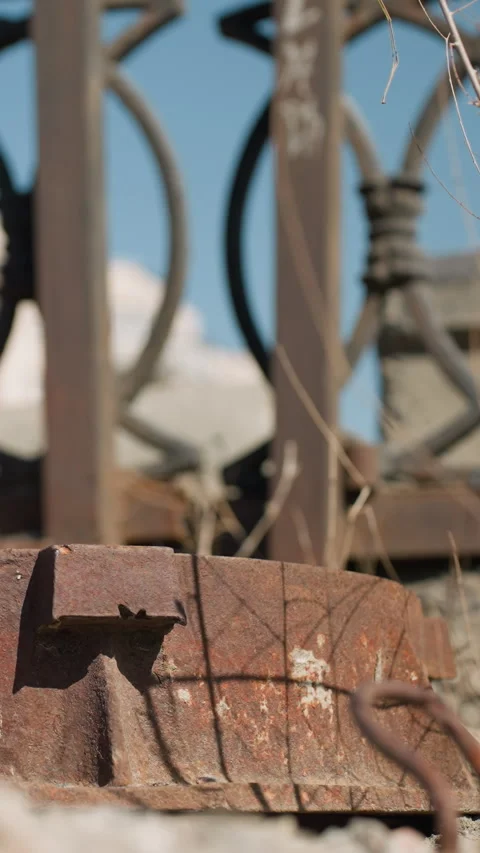 Close View of Rusty Metal Object with Ornate Urban Fence Background Stock Footage 310335494