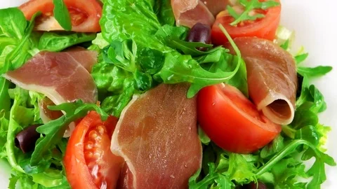 Close-up view of salad with ham, lettuce leaf, arugula, tomatoes and olives Stock Footage 73508106