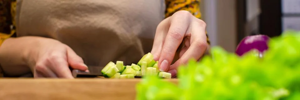 Close up view of the salad preparation process. A woman in an apron cuts a Foto stock