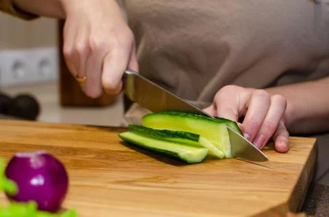Close-up view of the salad preparation process. A woman in an apron cuts a Stock Photos