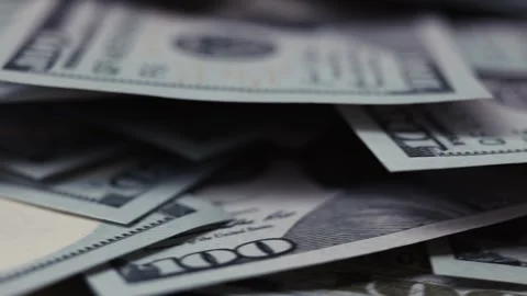 Close-up view of scattered hundred-dollar bills on a flat surface, showcasing Stock Footage 327717178