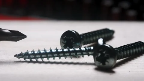 Close-up view of screwdriver bit and shiny metal screws on wooden surface i.. Stock Footage 312552477