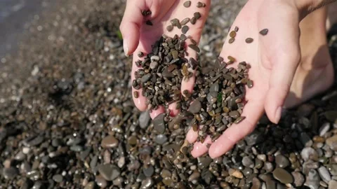 Close up view of sea sand running through a womans hands against a blurred ocean Stock-Footage 149280825