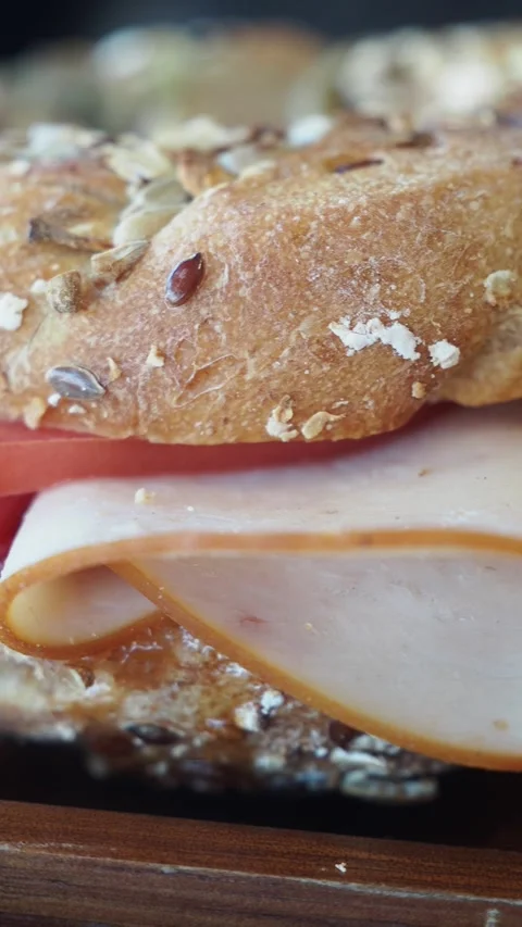 Close view of seeded bread and sliced deli meat on a sandwich Stock Footage 348472925