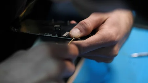 Close view serviceman screws iphone detail in workshop Stock Footage 104656229