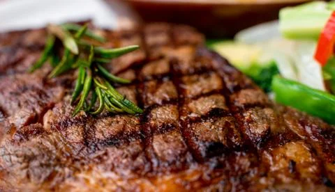 Close up view on serving of marinated grilled rib eye steak with baked potato Stock-Fotos