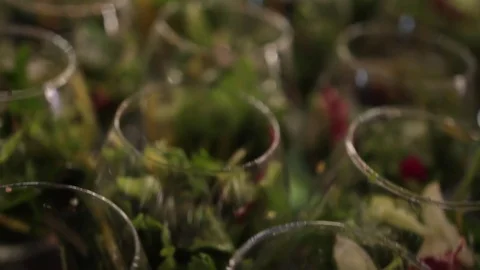 Close-up view on set of transparent glasses with salad and blur bokeh lights. Vidéo 72603198
