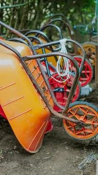 Close up view of several multi colored wheelbarrows parked in a garden area Stock Photos