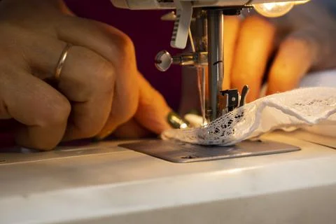 Close up view of sewing process. Female hands stitching white fabric on Stock Photos