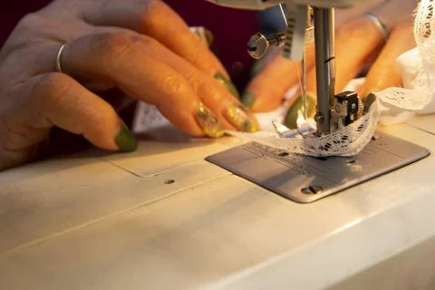Close up view of sewing process. Female hands stitching white fabric on profe Stock Photos