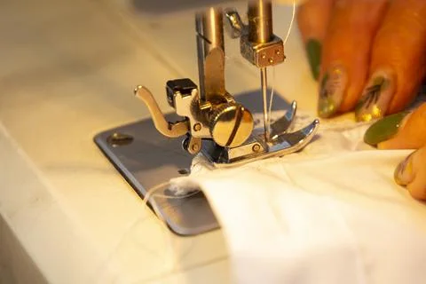 Close up view of sewing process. Female hands stitching white fabric on profe Stock Photos