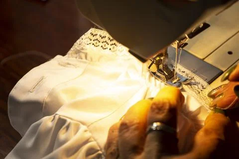 Close up view of sewing process. Female hands stitching white fabric on profe Stock Photos