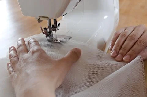 Close up view of sewing process. Female hands stritching white fabric Stock Photos