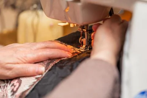 A close-up view of sewing process, hand of old woman using sewing machine Фото