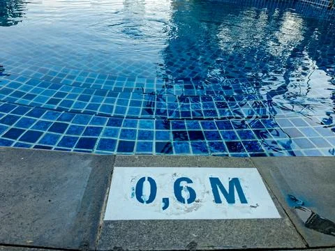 Close-up view of a shallow pool edge showing a "0,6 M" water depth marker p.. Stock Photos