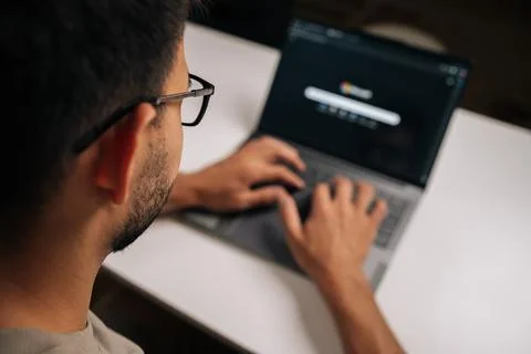 Close-up view from shoulder of office worker male wearing eyeglasses and typing 스톡 사진