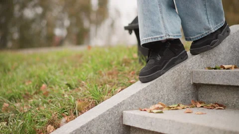 Close up view showing person black sneakers stepping down stone stairs with Stock Footage 346740699