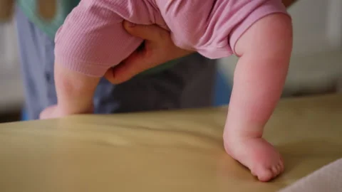 A close up view shows a baby's lower body while standing with support Vídeos de archivo 335355786