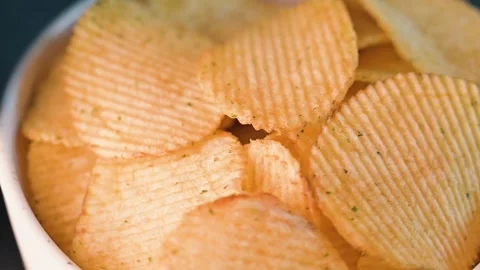 A close-up view shows a bowl filled with crispy potato chips ready for eating. Stock Footage 338297713