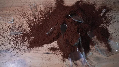 A close-up view shows coffee grounds spilled on a flat surface alongside broken Vidéo 344440834