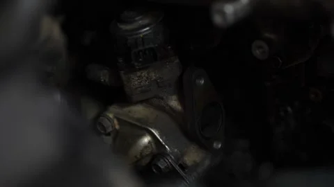 A close-up view shows a dirty car EGR valve or sensor assembly with an open m Stock Footage 345109969