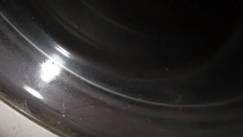 A close view shows the dusty curved metallic rim of a dark washing machine Stock Footage 330254727