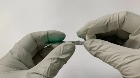 A close-up view shows a hand in gray rubber gloves holding pills. An empty Stock Footage 264293021
