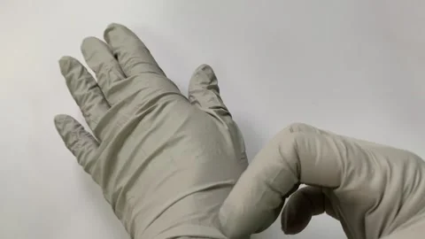 A close-up view shows a hand in gray rubber gloves holding pills. An empty Stock Footage 264294008