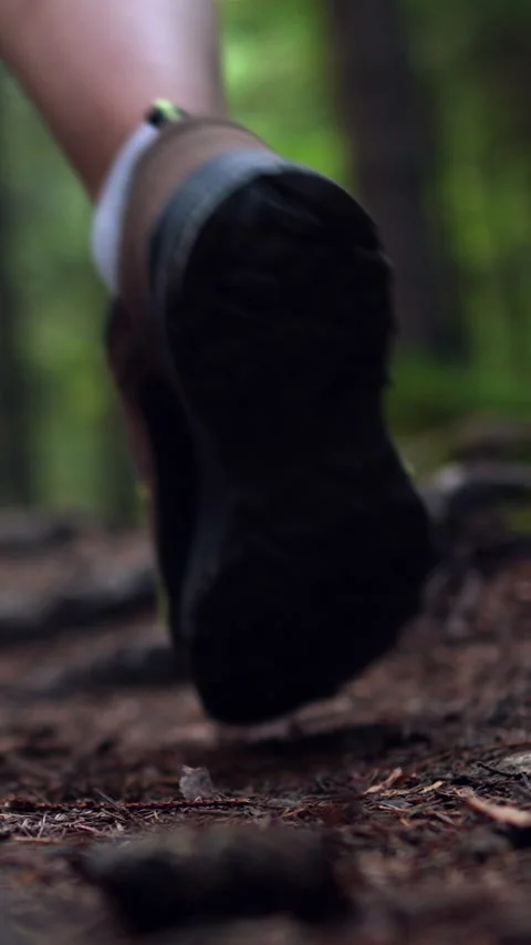 Close-up view shows tourist in bright hiking boots and a backpack stepping a Stock Footage 338200232