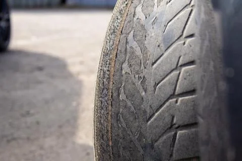 A close view shows a worn out car tire resting on a parking lot surface. Th.. Stock Photos