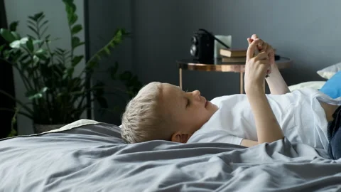 Close-up View from the Side A Child Boy Looks at the Phone Screen Plays a Game Stock Footage 156244981