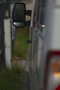 Close view of side mirror displaying traffic and roadside scene at dusk Photos
