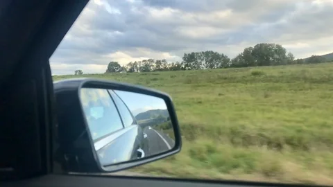 Close-up view of side mirror from vehicle on motorway. Driving a car along field Stock Footage 118249843