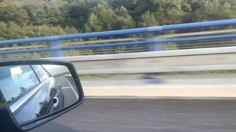 Close-up view of side mirror from vehicle on motorway. Driving a car along field Video stock 118250025