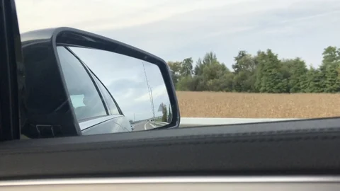 Close-up view of side mirror from vehicle on motorway. Driving a car along field Stock Footage 118250213