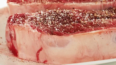 Close view on side of steak with fat being seasoned with salt. Stock Footage 258306825