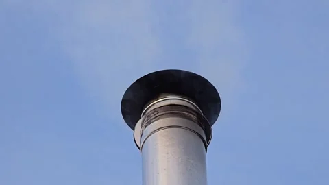Close view of a silver chimney smoking on a small wooden house with snow on.. Video stock 328163681