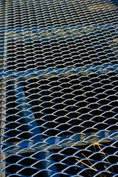 Close-up view of silver metal grating with diamond-shaped openings. Stock Photos