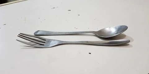 Close up view of a single spoon and fork in horizontal style Stock Photos