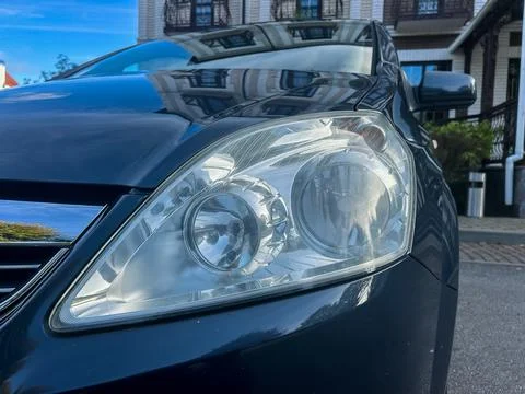 Close-up view of a sleek car headlight reflecting sunlight on a beautiful d.. Stock Photos