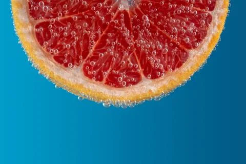 Close up view of a slice of grapefruit in soda water with bubbles. Stock Photos