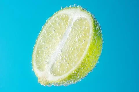 Close up view of a slice of lime in soda water with bubbles. Stock Photos