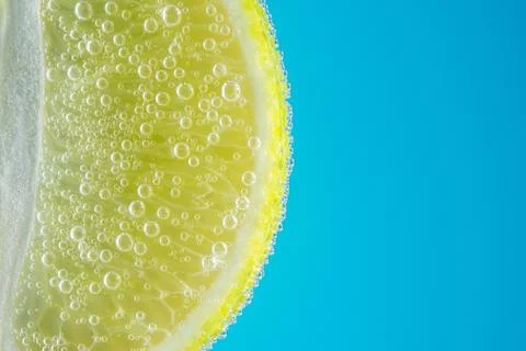 Close up view of a slice of lime in soda water with bubbles. Stock Photos